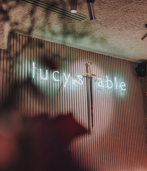 Neonverlichting met Lucy’s Table logo aan wand met zwaarddecoratie