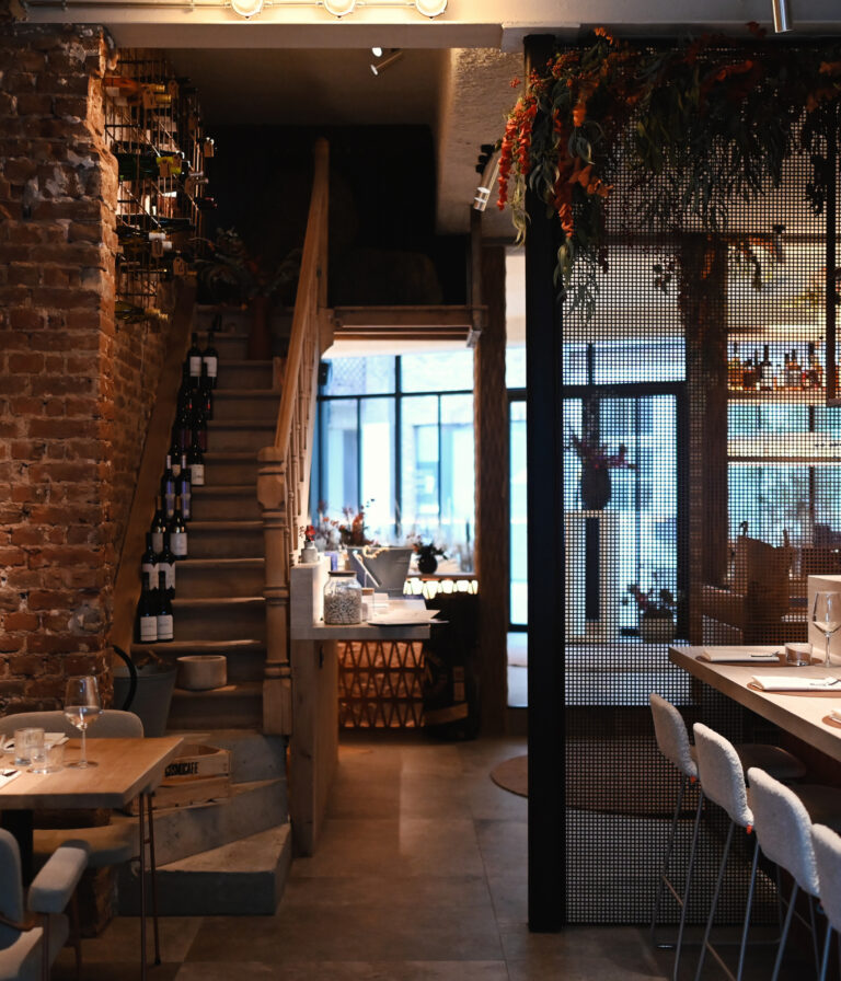Overzicht van de restaurantzaal van Lucy’s Table met trap en sfeervolle tafels